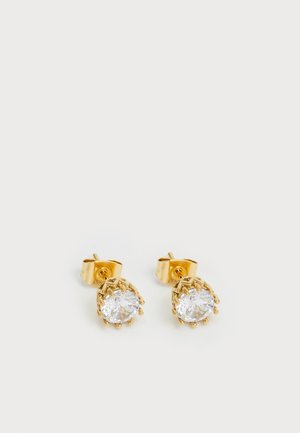 Pair of gold stud earrings with round clear gemstones held by prong settings on a plain white background.