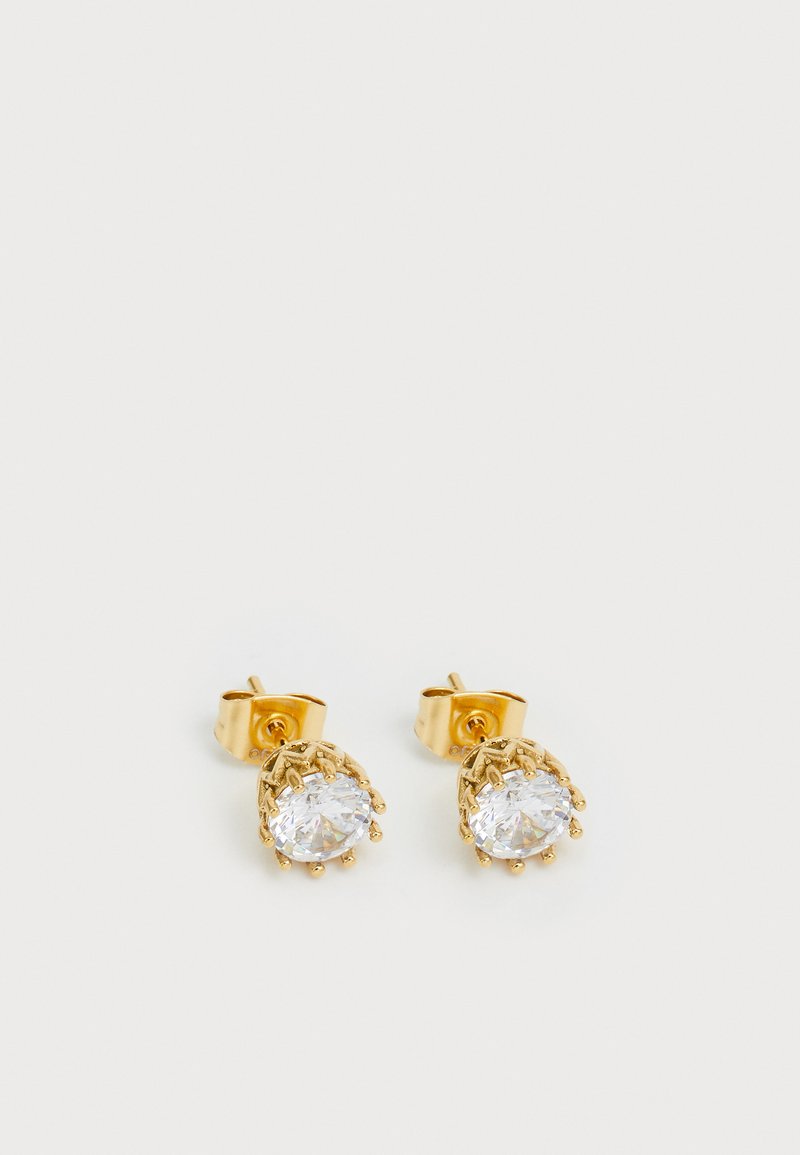 Une paire de boucles d'oreilles en or avec des pierres précieuses claires rondes maintenues par des griffes sur un fond blanc uni.