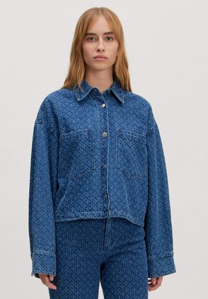 Kort denimjack in blauw met knoopsluiting, spitse kraag en twee voorkanten zakken, met een subtiel textuurpatroon.