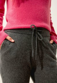 Grå, mjuka stickade sweatpants med elastisk midja och justerbar dragsko, ihop med en ljusrosa ulltröja med ribbade manschetter.