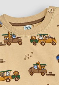 Felpa beige in cotone con scollo rotondo, caratterizzata da un motivo stampato di colorati camion giocattolo che trasportano animali e impronte di zampe.