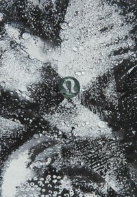 Tissu à motifs abstraits en noir et blanc avec des gouttes d'eau et un petit logo circulaire présentant une forme stylisée de "A" au centre.