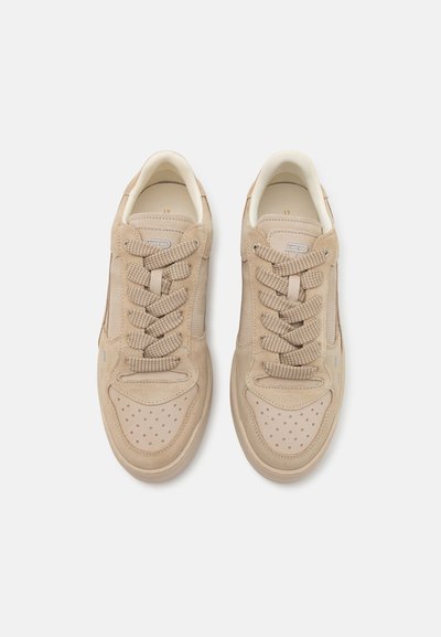 Zapatillas de ante beige con parte delantera perforada, cordones en color marrón y suela de goma clara. Presentan la marca en la lengua y en el lateral.