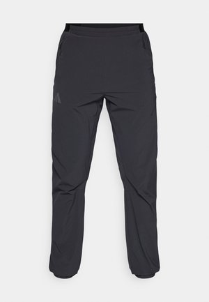 Herren schwarze wasserdichte Hose aus leichtem Stoff. Mit Reißverschlusstaschen und einem schlanken, zulaufenden Schnitt mit elastischem Bund.