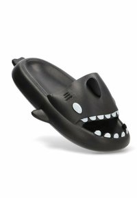 Chancleta de plástico negro con forma de tiburón, con una boca ancha, ojos blancos y detalles de dientes. Textura suave y diseño de parte trasera abierta.