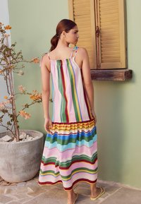 Multicolored striped maxi dress with a smocked upper section, ruffled hem, and thin shoulder straps. Light fabric with a relaxed fit.
