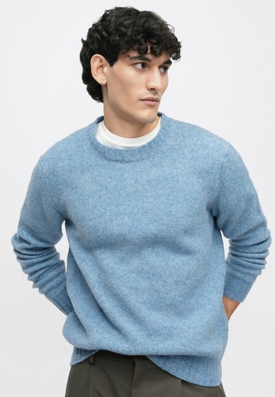 Világoskék gyapjúpulóver kerek nyakkivágással, bordázott mandzsettákkal és szegéllyel. Laza szabás, puha tapintás és oldalsó hasítékok az alján.