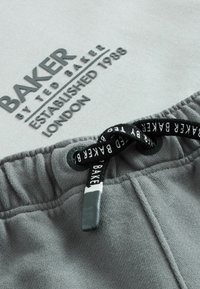 Grijze katoenen shorts met een trekkoord met merkaccenten, een zachte textuur en bedrukte logogegevens waaronder "BAKER" en "ESTABLISHED 1988."