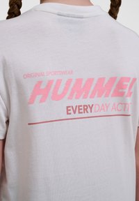 Weißes Baumwoll-T-Shirt mit großem pinken Grafikdruck auf der Rückseite, der "HUMMEL EVERYDAY ACT*" liest, und Rundhalsausschnitt.
