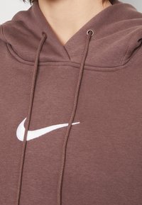 Felpa marrone con cappuccio in tessuto, con logo Nike bianco sul davanti e cordoncini regolabili sul cappuccio.