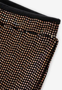 Tessuto nero decorato con paillettes metalliche circolari nelle tonalità del rosa antico. Il materiale è liscio con una leggera lucentezza, creando un aspetto testurizzato.