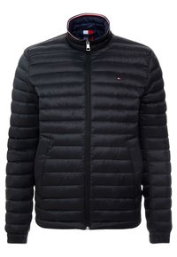 Svart puffjacka med dragkedja fram, med horisontellt kviltad design, ståkrage med röd och vit rand, samt logotyp på bröstet.