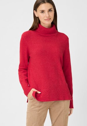 Roter Pullover mit geripptem Rollkragen und einem strukturierten Zickzackmuster entlang des unteren Saums. Hergestellt aus weichem Strickstoff.