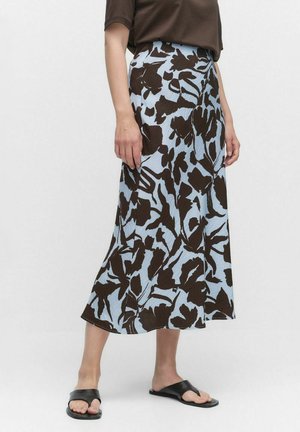 Blauwe rok met bloemenpatroon en bruine abstracte ontwerpen, knielang, gemaakt van lichtgewicht stof, gecombineerd met zwarte platte sandalen.