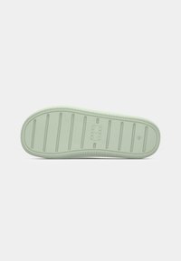Semelle d'une chaussure vert clair avec des rainures horizontales, une zone de logo rectangulaire et la taille 45 embossée près du talon.