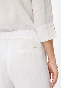 Witte linnen outfit met een ontspannen pasvorm, elastische tailleband en een klein, met rits afsluitbaar achterzakje met een metalen accent. Zachte, gestructureerde stof.