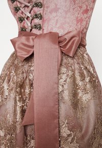Robe en brocart rose avec un corsage ajusté et un dos lacé, un nœud en satin à la taille, et une jupe ornée d’embellissements floraux et de perles.