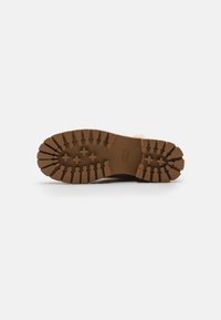 Brown rubber outsole with deep treads for traction. Structured design with a rounded toe and slight elevation at the heel.
