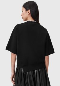 Felpa oversized in cotone nero con maniche corte e orlo a coste. Presenta un design pulito con cuciture minime e senza loghi visibili.