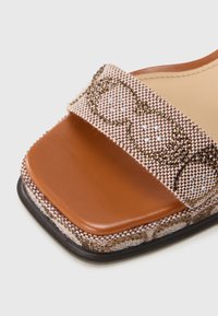 Καφέ δερμάτινο σανδάλι με πλ εγμένο μπεζ λουρί διακοσμημένο με μικρές καφέ και μπλε χάντρες, τετράγωνη μύτη και υφασμένο πάτο.