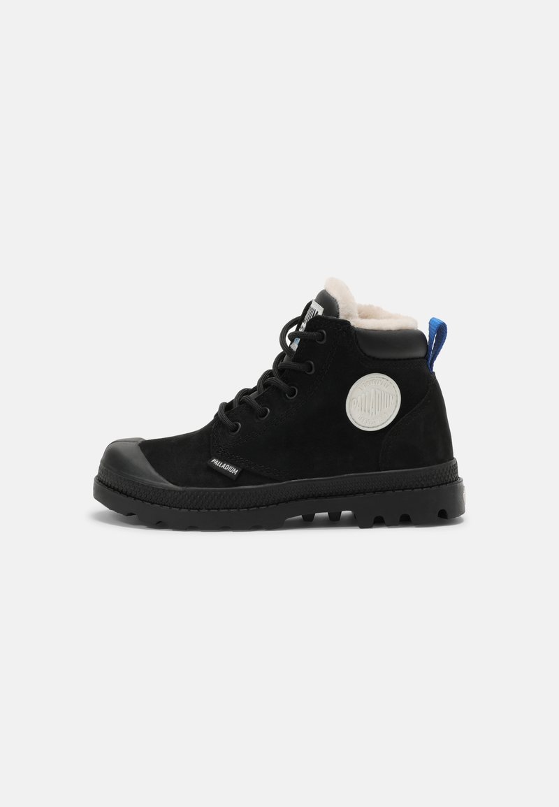 Bottines en daim noir avec embout en caoutchouc, semelle texturée, doublure en polaire blanche et écusson circulaire avec logo sur le côté. Tirette bleue à l'arrière.