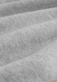 Pelēks audums ar gludu, strukturētu virsmu, kas izceļas ar smalkām krāsu un rakstu variācijām. Materiāls izskatās mīksts un elastīgs.