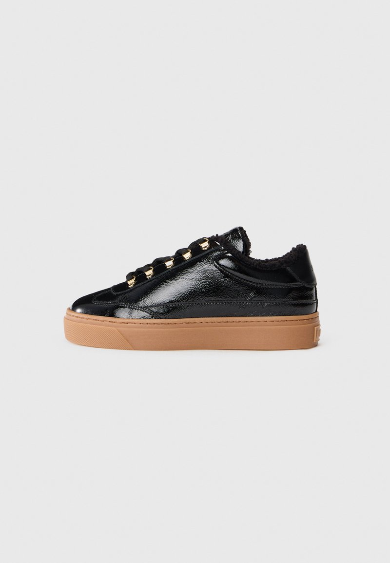 Baskets en cuir verni noir avec une semelle épaisse beige, des œillets en or, des lacets noirs et une doublure intérieure douce noire dans le col.