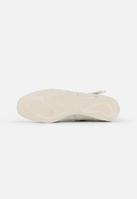 Lysfarget sneakers med en teksturert gummisåle med bølgedesign, stoffoverdel og justerbar stropp for en sikker passform.