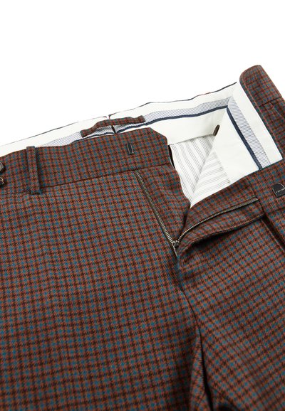 Bruine en blauwe houndstooth-gepatenteerde broeken met een open rits en zichtbare witte binnenvoering met blauwe strepen.