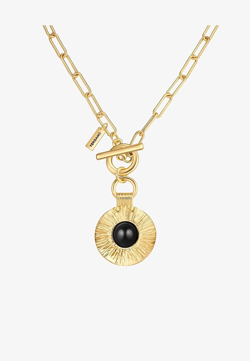 Zelta tonī ķēde ar apļveida piekariņu, kura virsma ir teksturēta un centrā ir melns akmens, nostiprināta ar slēdzeni.