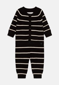 Body con maglia a righe nero e crema con maniche lunghe, scollatura rotonda e chiusura a bottoni; polsini e caviglie a coste. Tessuto morbido, vestibilità comoda.