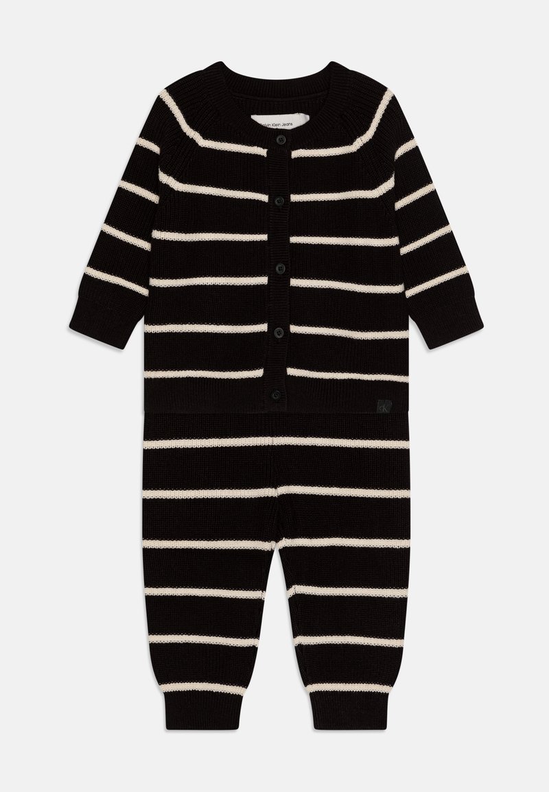 Body con maglia a righe nero e crema con maniche lunghe, scollatura rotonda e chiusura a bottoni; polsini e caviglie a coste. Tessuto morbido, vestibilità comoda.