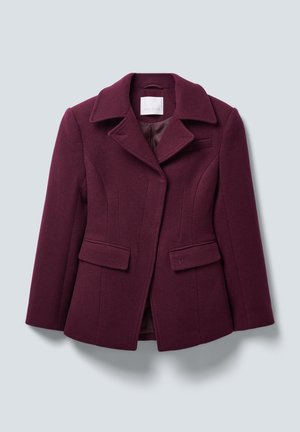 Kvinnelig skreddersydd mørk lilla ullblazer med brede revers, klafflommer og enknappdesign på en lys grå bakgrunn.