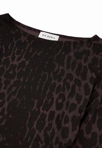 Schwarzes Oberteil mit einem Leopardenmuster in dunklen Brauntönen. Verfügt über einen weiten Ausschnitt und ein Etikett mit der Aufschrift "OH APRIL". Weiche Stofftextur.