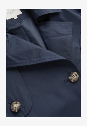 Navy blue coat with large tortoiseshell buttons, visible pocket, and "Celibes of Sweden" label inside collar.
