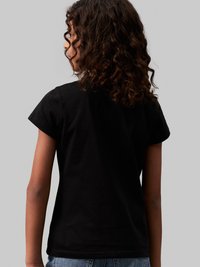 Camiseta negra de manga corta, hecha de algodón, con un corte simple y un diseño de espalda sin costuras. Apta para uso casual.
