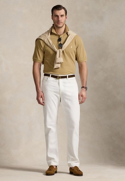 Khaki polo shirt, white pants, beige sweater draped on shoulders, brown belt, brown shoes, and black sunglasses. Plain background.