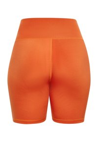 Oranssit urheilushortsit, joissa on korkea vyötärö ja jotka on valmistettu sileästä, joustavasta materiaalista. Ominaisuuksiin kuuluvat litteät saumat ja tiukka malli.