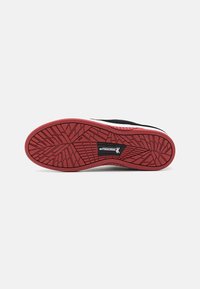 Black sneaker outsole with a red rubber bottom, featuring a geometric tread pattern and branding in the center. Smooth texture with a durable design.