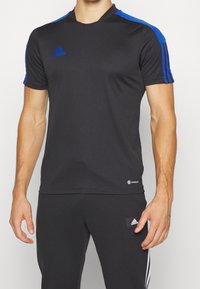 Camiseta deportiva de manga corta negra con acentos azules en los hombros, hecha de un tejido ligero, con el logo de Adidas y la etiqueta Aeroready.