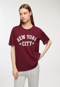 T-shirt in cotone bordeaux con maniche corte e scollatura rotonda, con la scritta bianca "NEW YORK CITY 93" in evidenza.