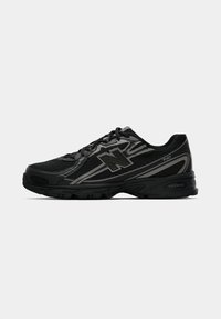 Chaussure de sport noire avec une tige en mesh, comportant des accents gris, une semelle rembourrée et un logo "N" bien visible sur le côté.