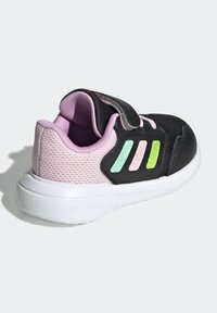 Chaussure de sport noire et rose avec dessus en mesh, bride à velcro, semelle blanche et trois bandes colorées (aqua, rose, vert) sur le côté.