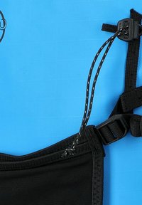 Cinghia nera regolabile con fibbia in plastica e fermacorde su sfondo azzurro brillante e testurizzato.