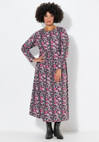 Blumen-Maxikleid mit langen Ärmeln; schwarzer Hintergrund mit rosa und weißen Blumen. Strukturierter Stoff und taillierter Schnitt betonen die Silhouette.