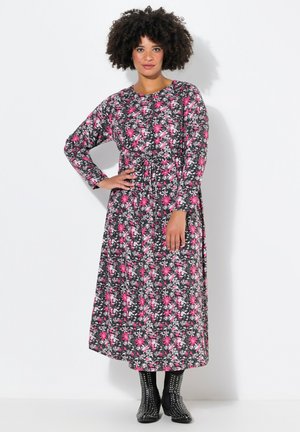 Blumen-Maxikleid mit langen Ärmeln; schwarzer Hintergrund mit rosa und weißen Blumen. Strukturierter Stoff und taillierter Schnitt betonen die Silhouette.