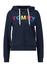 Navy zip-up hoodie made of cotton blend; features white drawstrings, side pockets, and colorful "TOMMY JEANS" logo in red, yellow, and blue.