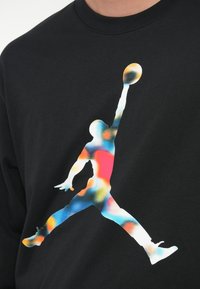 Μαύρο πουκάμισο με μακριά μανίκια, featuring μια πολύχρωμη γραφική παρ�άσταση ενός άλματος με μπάσκετ, που επιδεικνύει μπλε, κόκκινες και κίτρινες αποχρώσεις.