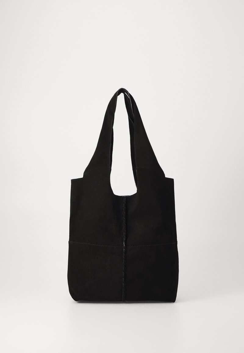 Sac fourre-tout en daim noir avec de larges poignées et une couture verticale au centre, présenté sur un fond blanc uni.