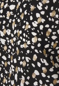 Musta kangas, jossa on hajautettu kuvio valkoisista ja kultaisista pisteistä. Pisteillä on teksturoitu, metallinen kiilto, joka luo kontrastia taustan kanssa.